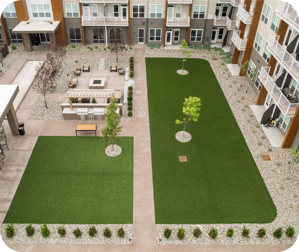 Aerial view of professionally landscaped apartment complex courtyard featuring manicured lawns, outdoor seating areas, and strategic plantings for commercial property enhancement