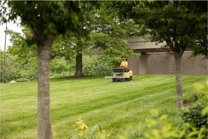 commercial-lawn-mowing-maintenance-cleveland-ohio H&M Landscaping professional performing commercial lawn maintenance with riding mower on corporate property in Cleveland Ohio