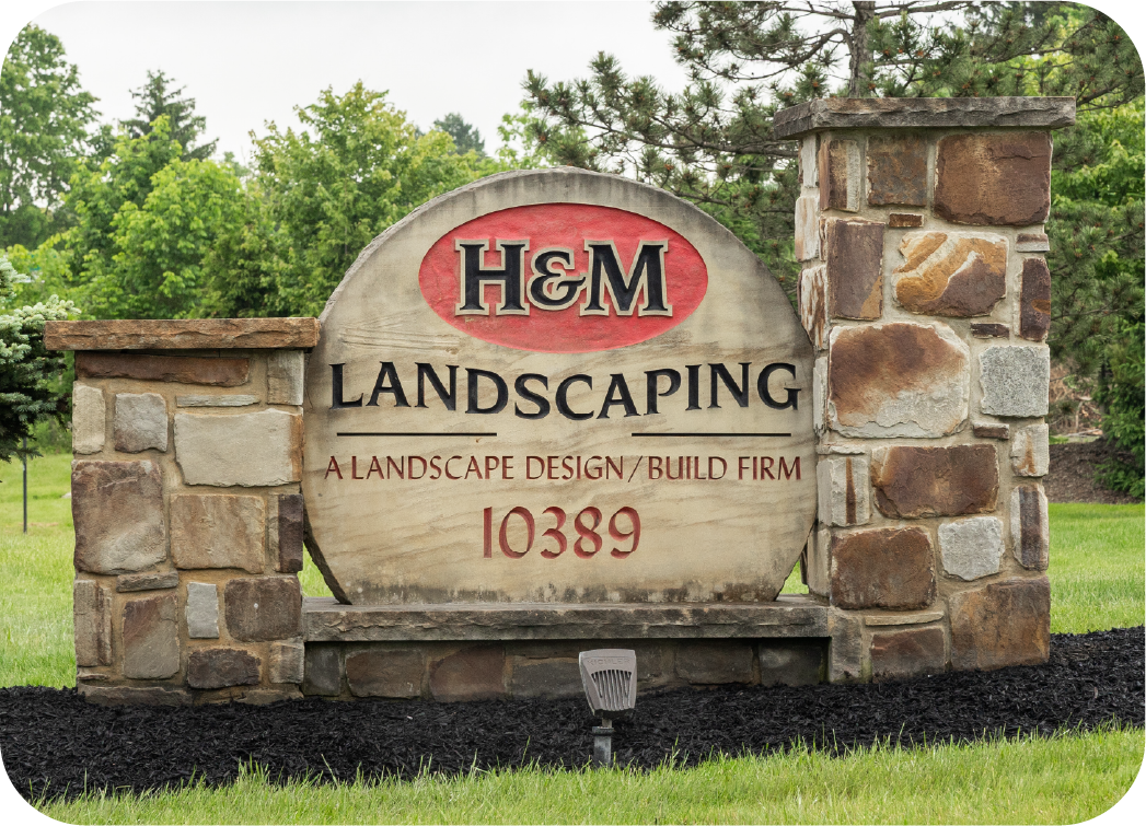 hm-landscaping-entrance-monument-sign H&M Landscaping professional stone monument entrance sign displaying company logo and address 10389, showcasing quality landscape design and build craftsmanship