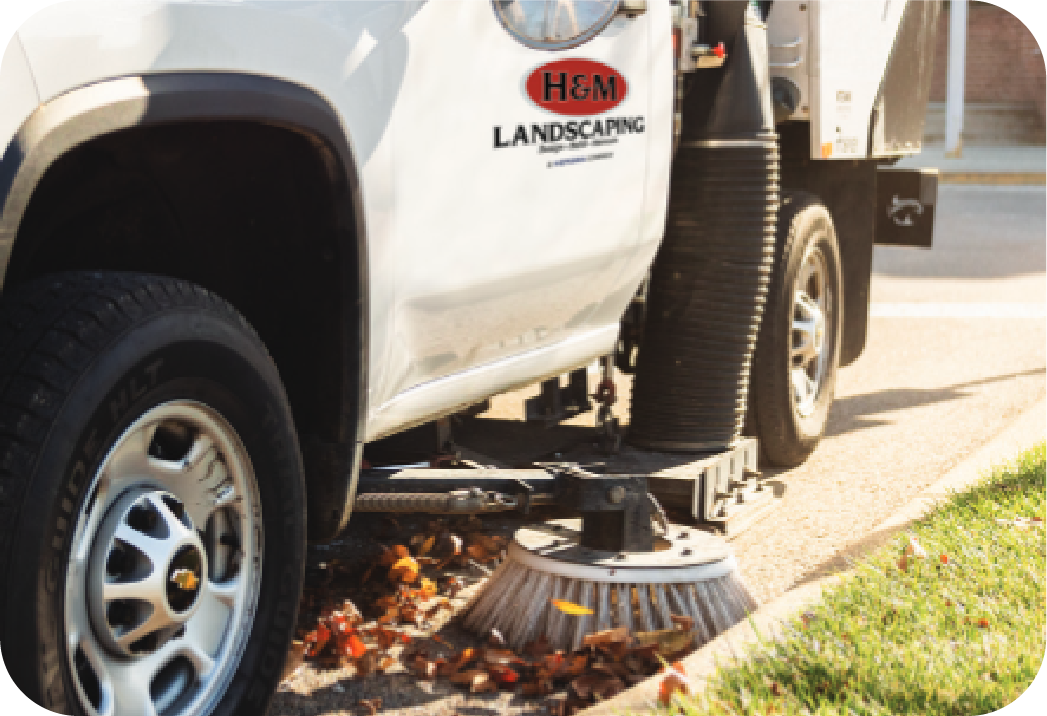 hm-landscaping-sweeper-truck-cleaning H&M Landscaping branded sweeper truck performing parking lot cleaning services, showing professional commercial property maintenance in action
