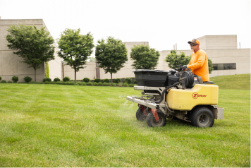 lawn-fertilization-service-ohio Landscaping professional applying fertilizer with a ride-on spreader for healthy green grass